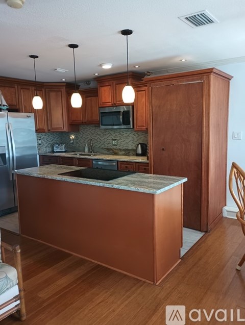 A kitchen with wooden cabinets and a marble island.