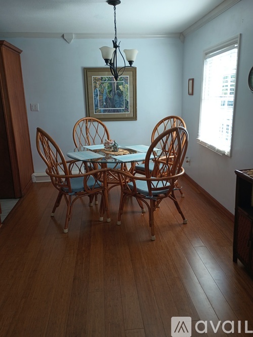 A wooden dining table with chairs and a painting on the wall.