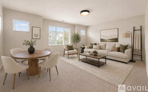 A living room with a round wooden table surrounded by white chairs.