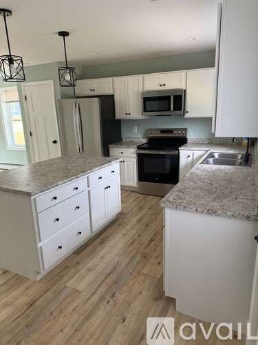 A kitchen with white cabinets and a granite countertop.