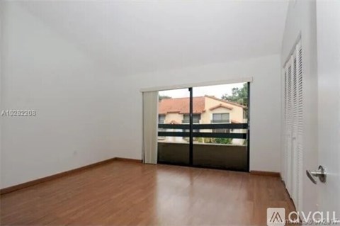 A room with wooden flooring and a sliding glass door leading to a balcony.