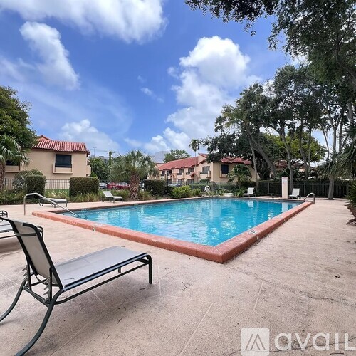 A pool surrounded by a concrete patio and trees.