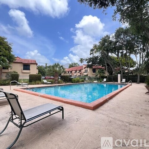 A pool surrounded by a concrete patio and trees.