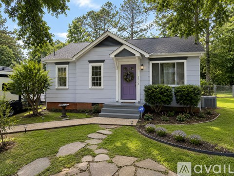 A house with a purple door and a stone pathway leading to the front door.