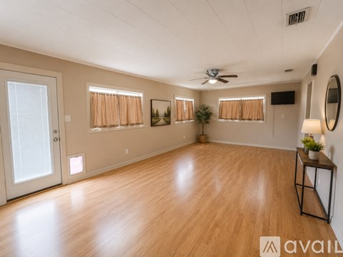 A spacious room with wooden flooring and a ceiling fan.