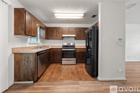 A kitchen with wooden cabinets and a black refrigerator.