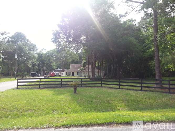 A house is surrounded by a fence and trees.
