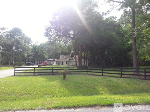 A house is surrounded by a fence and trees.
