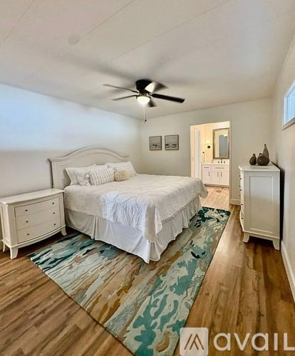 A bedroom with a bed, dresser, and ceiling fan.