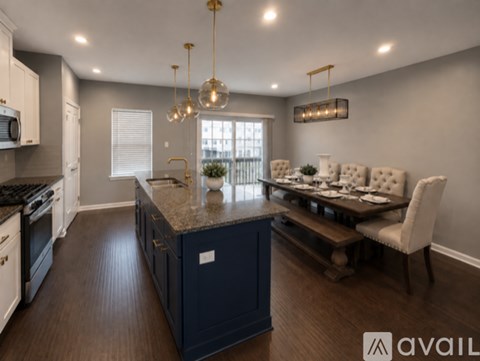 A modern kitchen with dark blue cabinets and a dining area with white chairs.