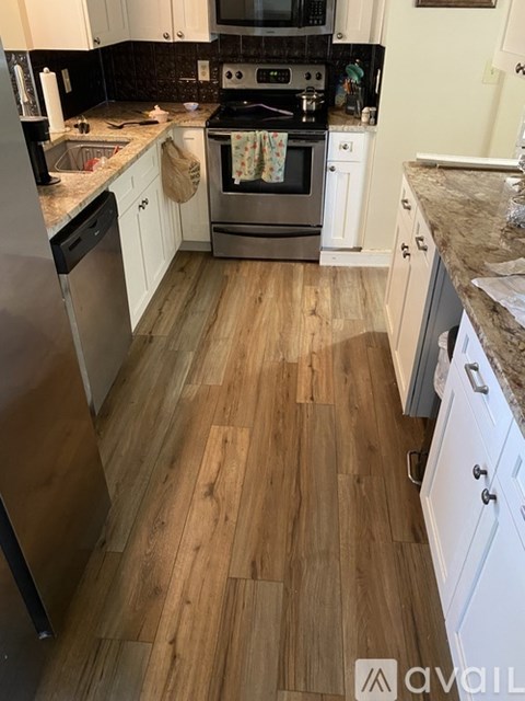 A kitchen with wooden floors and white cabinets.
