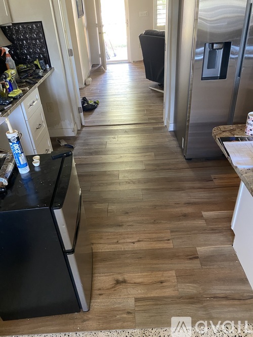 A kitchen with a black fridge and wooden floors.