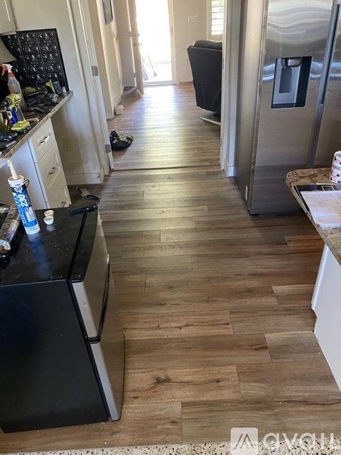 A kitchen with a black fridge and wooden floors.