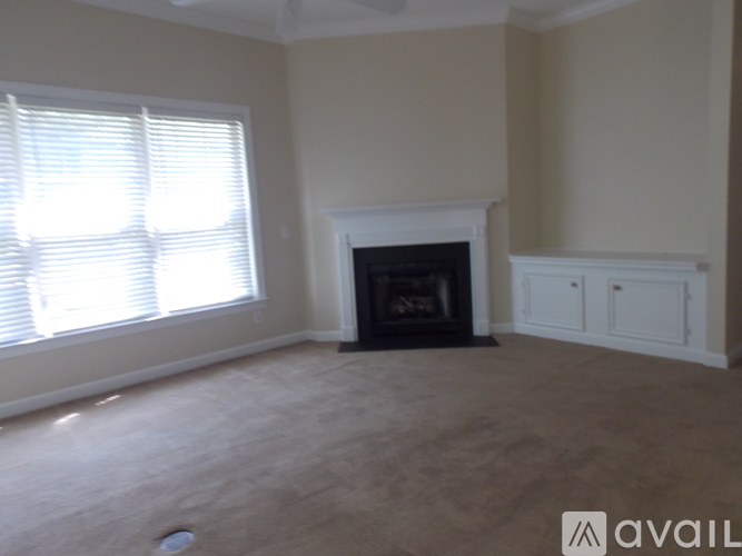A living room with a fireplace and a window with blinds.