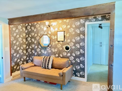 A living room with a couch and a floral wallpaper.