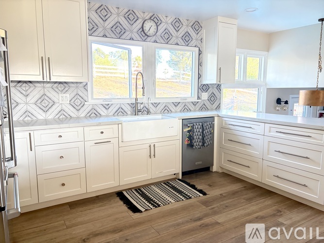 A kitchen with white cabinets and a patterned tile backsplash.
