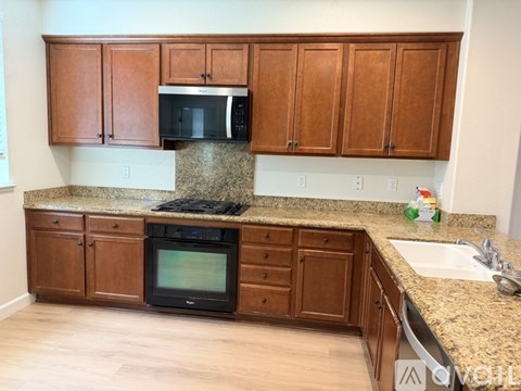 A kitchen with brown cabinets and granite countertops.