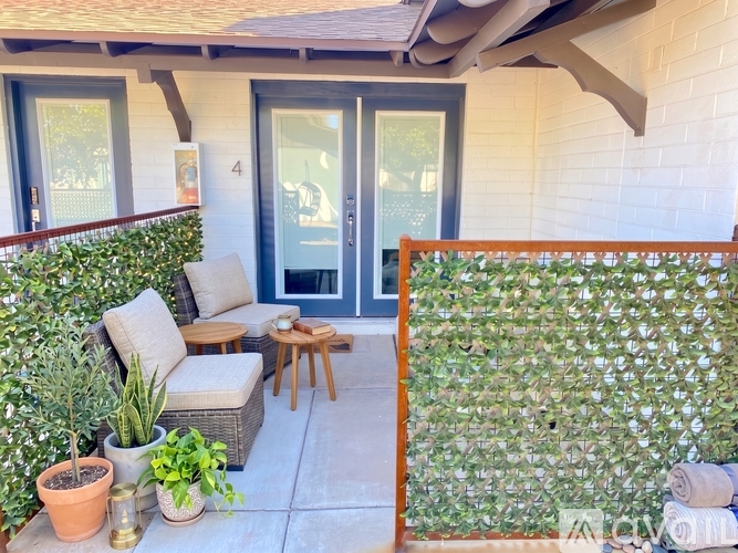 A patio with a chair, table, and potted plants.