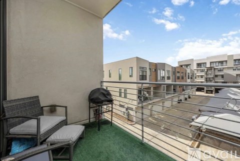 A balcony with a chair and a table is overlooking a courtyard.