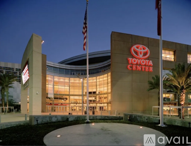 A Toyota Center building with a large glass front and two flags on either side.