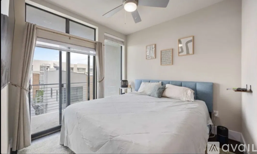 A bedroom with a large bed and a sliding glass door leading to a balcony.