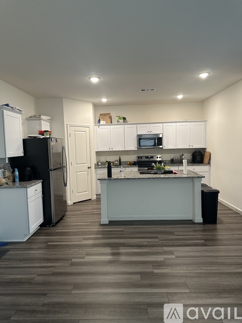 A kitchen with a black fridge and white cabinets.