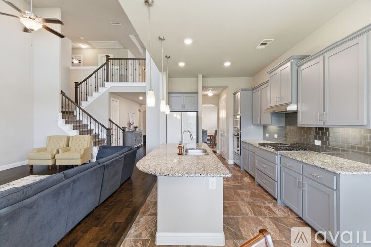 A kitchen with a marble island and a staircase in the background.