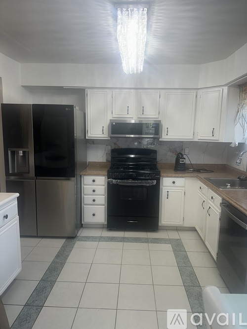A kitchen with white cabinets and a black fridge.