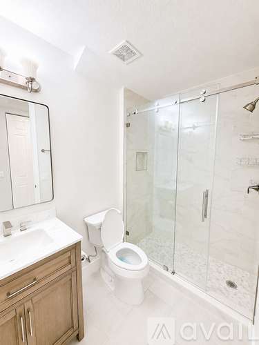 A white bathroom with a toilet, sink, and walk-in shower.