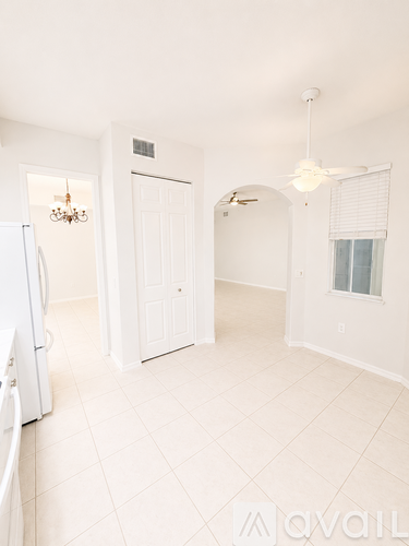 A white kitchen with a fridge and a fan.
