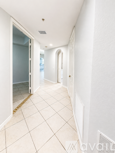 A long white hallway with tiled flooring and white walls.