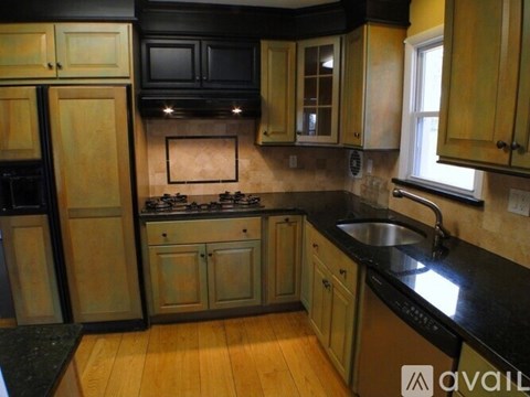 A kitchen with wooden cabinets and black countertops.