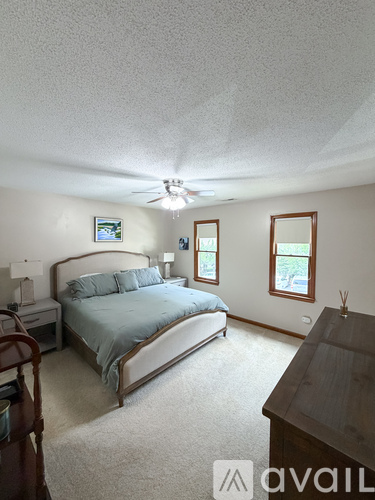 A bedroom with a bed, dresser, and ceiling fan.