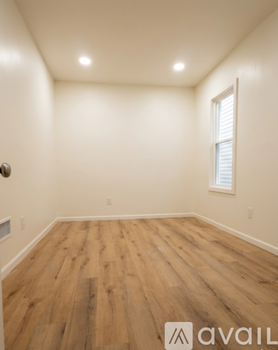 A room with wooden flooring and a window with blinds.