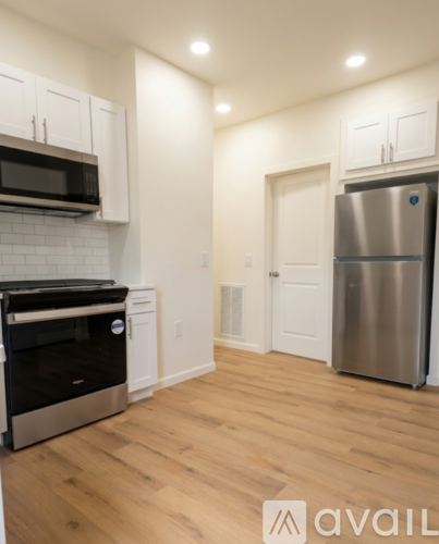 A kitchen with a stainless steel refrigerator and wooden floors.