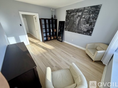 A living room with a white sofa and a black and white painting on the wall.