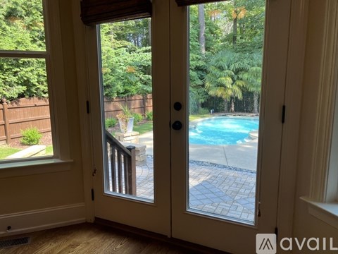 A view of a pool through a sliding glass door.