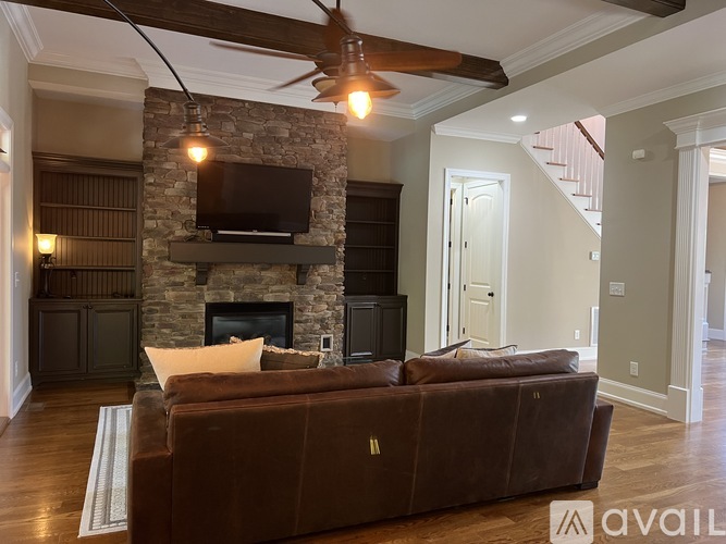 A living room with a stone fireplace and a brown couch.
