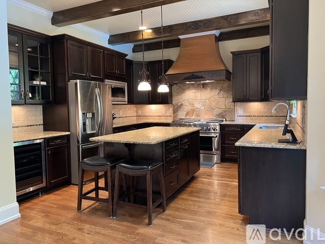 A kitchen with dark wood cabinets and a stone backsplash.