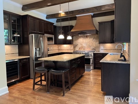 A kitchen with dark wood cabinets and a stone backsplash.