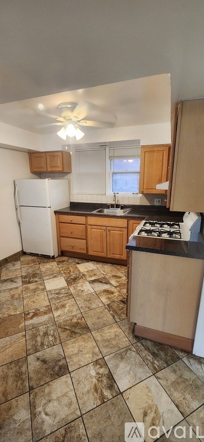 A kitchen with a white refrigerator and brown cabinets.