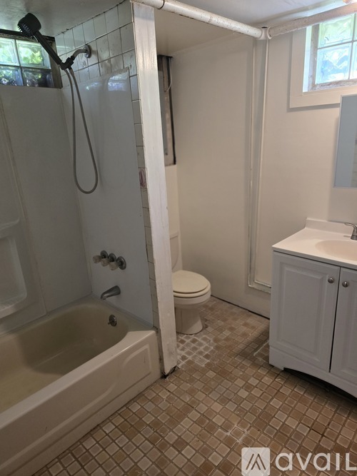 A bathroom with a white tub and toilet, a sink, and a window.