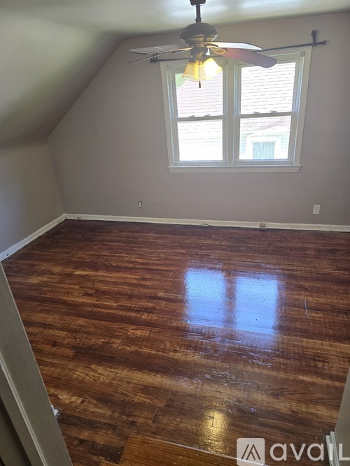 A room with wooden flooring and a ceiling fan.