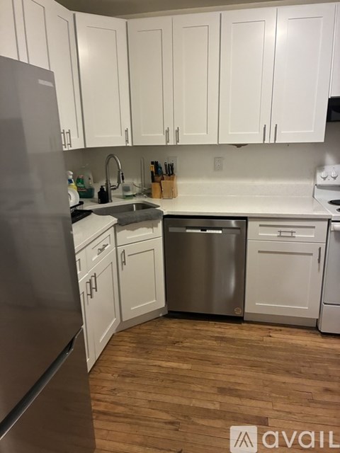 A kitchen with white cabinets and a wooden floor.