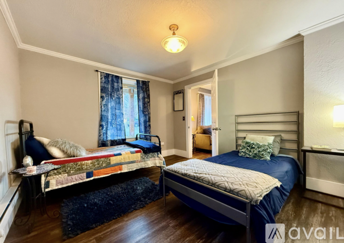 A bedroom with two beds and a window with curtains.