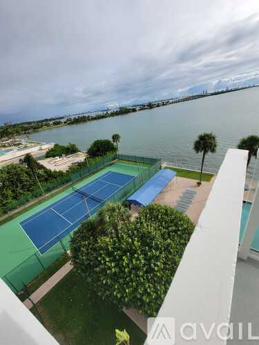 Tennis courts with a view of the water and a bridge in the distance.