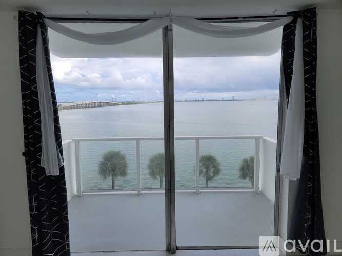 A balcony with a view of the water and trees.