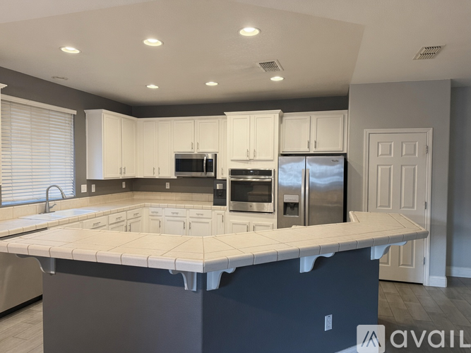 A kitchen with a large island in the middle and stainless steel appliances.