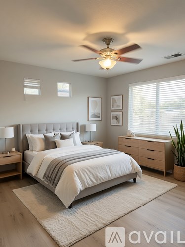 A bedroom with a large bed, a ceiling fan, and a nightstand with a lamp.