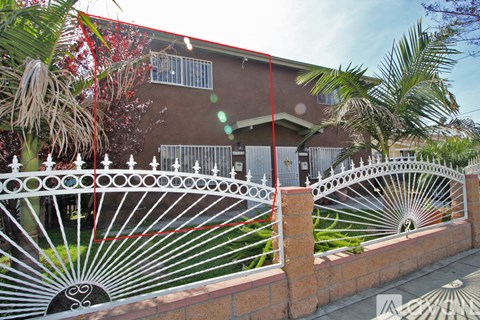 A red fence with a white design is in front of a house.